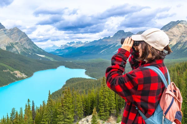 Dürbün kullanan kadın yürüyüşçü, Peyton Gölü 'nün büyüleyici turkuaz sularına ve Banff Ulusal Parkı' ndaki görkemli dağlara Alberta 'nın nefes kesici vahşi doğasına hayran.