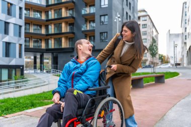 Bakıcılar, tekerlekli sandalyeli bir adamı şehir caddesinde gezdirirken gülüp sohbet ederken aynı zamanda ulaşılabilir bir şehir gezintisinin ve destekleyici bir arkadaşlığın tadını çıkarıyorlar.