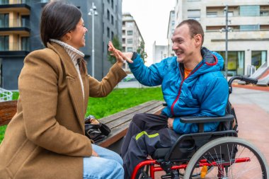 İki arkadaş gülüyor ve dışarıda bir beşlik çakıyor, sevinçle ve cesaretle olan ilişkilerini kutluyorlar, desteği, dahil edilmeyi ve pozitif bir ilişkiyi sembolize ediyorlar.