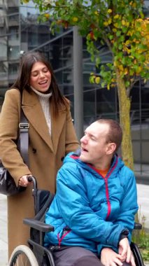 Kentte yürüyüş yaparken engelli bir adama yardım eden genç bir kadın bakıcı, engelli insanları şehir ortamında tedavi, destek ve kapsama gösteriyor.