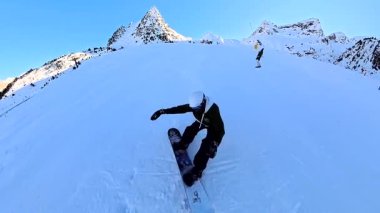 Güneşli bir günde, karlı bir dağ yamacında kar kayağı yapan, kış sporlarının keyfini çıkaran ve güzel bir kayak merkezinin taze tozunu oyan ilk kişi.