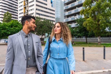 İş arkadaşları çağdaş bir kentsel alanda yürürken, modern bir şehir ortamında takım çalışması, ağ oluşturma ve profesyonel etkileşim sunarken,