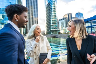 Çeşitli iş adamları modern bir şehir ortamında neşeli bir açık hava sohbeti ve ağ kurma oturumu yaparak takım çalışmalarını ve olumlu etkileşimleri teşvik ediyorlar.