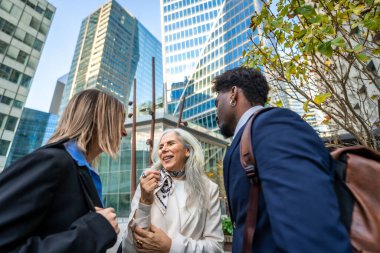 Modern bir ofis bölgesinde iş birliği yapan, iletişim kuran, gülümseyen ve ilişkiler kuran çeşitli iş adamları grubu.