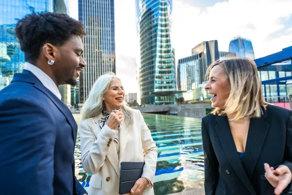 Çeşitli iş adamları modern bir şehir ortamında neşeli bir açık hava sohbeti ve ağ kurma oturumu yaparak takım çalışmalarını ve olumlu etkileşimleri teşvik ediyorlar.