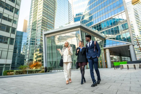 Çağdaş bir finans bölgesinde yürüyen ve tartışan çeşitli iş adamları, işbirliği, kentsel iş hayatı ve uluslararası iş ağlarını yansıtıyorlar.