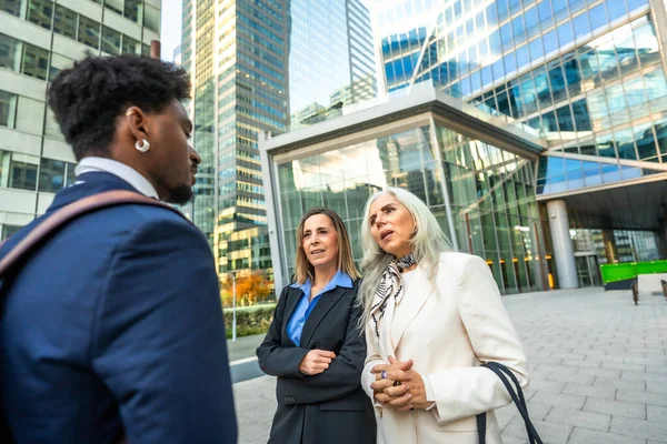 Çeşitli iş adamları gayri resmi bir açık hava toplantısı yapıyor, fikirleri tartışıyor ve ofis binalarıyla modern şehir ortamında bir proje üzerinde işbirliği yapıyorlar.