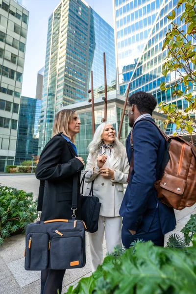 Profesyonel meslektaşlar dışarıda duruyor, modern şehir gökdelenleri arasında işbirlikçi bir tartışma ve ağ kuruyor, çeşitli kuşakları ve geçmişleri temsil eden bir iş toplantısında.