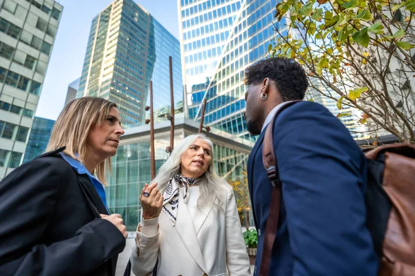 Profesyoneller ofis binaları dışında odaklı bir sohbete girişiyor, şehir ortamında işbirliği, takım çalışması ve modern kurumsal iletişimi temsil ediyorlar.