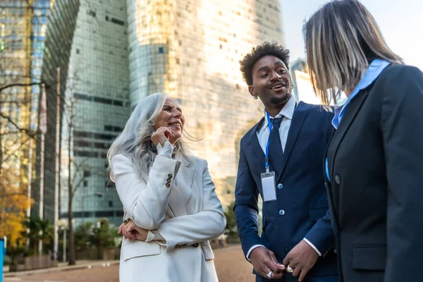 Çeşitli iş adamları, şehir ortamında neşeli bir sohbet ve açık hava ağı paylaşıyor, işbirliği ve takım çalışması sergiliyor.