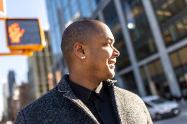 Profesyonel bir adam canlı şehir sokaklarında rahatça yürüyor, mutlu bir ifadeyle ileriye bakıyor, şehir merkezindeki başarılı iş hayatı tarzını canlandırıyor.