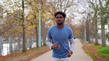 Mutlu Afrikalı genç Amerikalı adam Paris, Fransa 'daki bir şehir parkında sabah koşusundan keyif alıyor. Sağlıklı ve aktif bir yaşam tarzı sürdürüyor. Gülümsüyor ve sonbaharda açık havada egzersiz yapıyor.