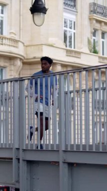 Spor giysili Afro-Amerikalı bir adam Paris 'teki sabah antrenmanı sırasında köprüde koşuyor ve merdivenlerden aşağı koşuyor. Sağlıklı ve aktif bir yaşam tarzını somutlaştırıyor.