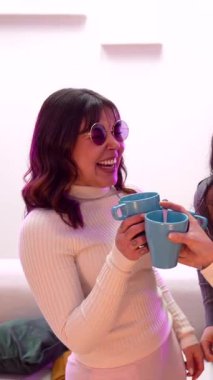 Rengarenk güneş gözlüklü mutlu bayan arkadaşlar fincanlarla kadeh kaldırıyor, gülüyor ve birlikte dans ediyor eğlenceli bir pijama partisinde arkadaşlığımızı kutluyor ve kaygısız bir anın tadını çıkarıyoruz.