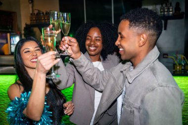 Çeşitli yetişkin arkadaşlar kadehlerinde şampanya kadehleri kaldırıyor, canlı bir kulüpte ya da bar ortamında özel bir olayı ya da parti olayını kutluyorlar.