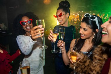 Çeşitli genç kadınlar geceyi dışarıda kutluyor ve şampanyayla kadeh kaldırıyor. Şenlikli bir parti sırasında, parlak ışıklar ve parlak süslemeler ile bir kulüp ortamında.