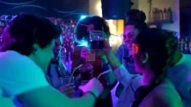 Dans eden, kokteyl içen ve neon ışıklı bir gece kulübünde kadeh kaldıran çok ırklı bir arkadaş grubu. Gençler neşeli bir sosyal etkinlikte eğleniyor, gülüyor ve kutlama yapıyorlar.