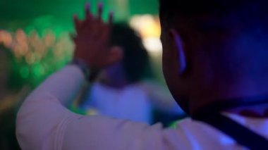 Partide dans pistinde dans eden mutlu genç ve çok ırklı arkadaşlar kalabalık bir gece kulübünde renkli neon ışıklarıyla müzik ve canlı atmosferin tadını çıkarıyorlar.