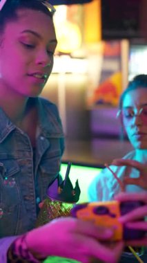 Doğum gününü kutlayan, kokteyl içen, dans eden renkli neon ışıkları olan canlı bir barda köpükler üfleyerek eğlenceli ve enerjik bir parti atmosferi yaratan genç kadınlar.