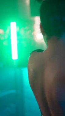 Bir parti sırasında dans pistinde arkadaşlarıyla dans edip gülen mutlu genç kadınlar. Canlı yeşil ve mor neon ışıklar gece kulübünü aydınlatıyor. Birlikte eğlenceli bir gece geçiriyorlar.