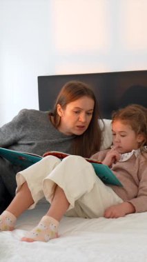 Sevgi dolu bir anne, yatmadan önce küçük kızına ilginç bir kitap okur, yatmadan önce sıcak bir aile anı yaratır ve sıcak bir yatak odasında güzel vakit geçirir.