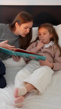 Sevecen bir anne, yatmadan önce kızına ilginç bir kitap okuyor, güzel bir anı paylaşıyor ve akşamları yatakta rahat bir şekilde yatıyor.