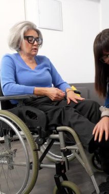 Tekerlekli sandalyedeki yaşlı, engelli bir kadına yardım eden hemşire, onu bakım evinden dışarı çıkmaya hazırlarken, özveri, şefkat ve destek gösteriyordu.