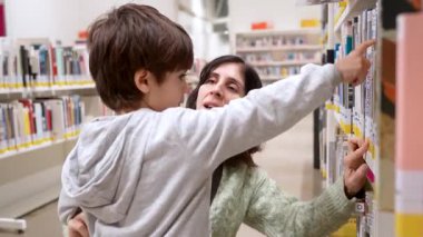 Genç bir anne, halk kütüphanesindeki bir kitaplıkta çocuk kitabı ararken meraklı küçük oğlunu kucağında tutuyor ve birlikte geçirdikleri aile zamanlarında okuma ve öğrenme sevgisi besliyor.