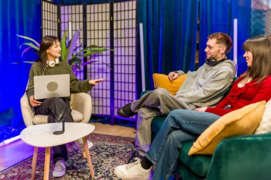 Genç çeşitli yaratıcılar şık bir stüdyoda podcast kaydediyor, mikrofonlar ve dizüstü bilgisayarların etrafında sohbet ediyor, dijital içerik ve sosyal medya izleyicileri için işbirliği yapıyorlar.