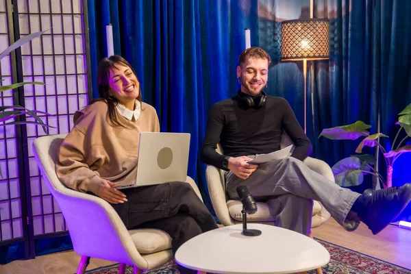 İçerik yaratıcıları sosyal medya için bir podcast veya canlı yayın kaydediyor, profesyonel ekipmanlarla dolu modern bir stüdyoda rahatça oturuyor, çevrimiçi platformlar için yeni malzemeler üretiyorlar.