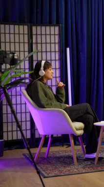 Sosyal medya için içerik yaratan genç erkek ve kadın, profesyonel ışıklandırma ve ekipmanlarla şık bir stüdyoda otururken bir röportaj podcast 'i veya canlı yayın oturumunu kaydediyor