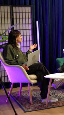 Genç nüfuzlu kişiler podcast tartışması ya da profesyonel ışıklandırması olan bir stüdyoda sohbet programı, tripoda kamera ve küçük bir masada mikrofon kaydediyor.