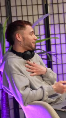 Bir podcast röportajı sırasında canlı bir konuşma yapan, fikirleri paylaşan ve profesyonel mikrofonlarla modern bir içerik yaratma stüdyosunda birbirleriyle meşgul olan üç genç etken.