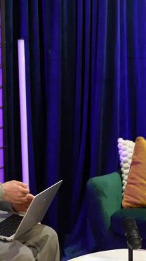 Genç içerik yaratıcıları bir podcast kaydediyor ya da modern bir stüdyoda canlı yayın yapıyorlar. Neon ışıkları, mikrofon ve rahat koltukları olan, çevrimiçi izleyicilerine bağlanıyorlar.