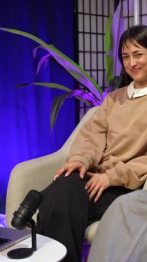 Mutlu bir genç adam ve kadın podcast yaparken ya da canlı yayın yaparken beşlik çakıyor, modern bir içerik yaratma stüdyosunda mikrofon ve dizüstü bilgisayarla yan masada birlikte gülüyorlar.