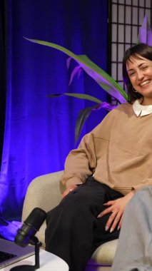 Gülümseyen genç kadın ve erkek podcast röportajını ya da talk show 'u bitirdikten sonra mutlu bir şekilde kucaklaşıyorlar. Modern bir stüdyoda otururken arkadaşlıklarını ve iyi ilişkilerini gösteriyorlar.