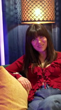 Neşeli kadın içerikli yaratıcılar bir koltukta oturup canlı yayında podcast röportajı sırasında konuşuyorlar, profesyonel bir stüdyoda seyircileri için sosyal medya içeriği yaratıyorlar.