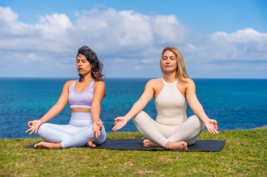 İki kadın, güneşin doğuşuyla birlikte yoga ve meditasyon yaparak bir hasırın üzerinde oturur. Huzur, denge ve doğa ve birbirleri ile bilinçli bir bağ kurarlar.