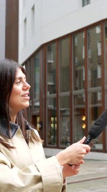 Profesyonel kadın muhabir mikrofon tutuyor ve şehir sokaklarında genç bir zenciyle röportaj yapıyor. Bir haber bölümü ya da belgesel için verdiği tepkileri kentsel bir ortamda yakalıyor.