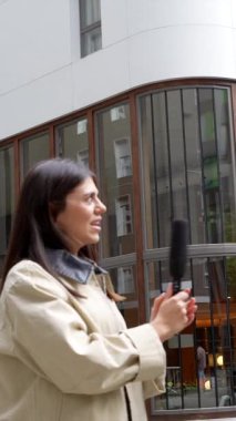 Elinde mikrofon olan genç bir kadın muhabir, bir haber bülteni ya da podcast için kamuoyunu yakalayan, gülümseyen bir Afrikalı Amerikalı adamla vox pop röportajı yapıyor.