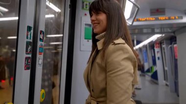 Modern bir yeraltı treninin içinde duran mutlu kadın, durmasını beklerken gülümsüyor, kapıyı açmak için düğmeye basıyor ve arabadan iniyor.