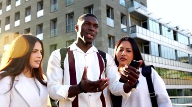 Şehrin dışında duran çok kültürlü genç meslektaşlar. Yol tarifi ya da bilgi için akıllı telefonu kullanmak. Bir sorunu çözmek için işbirliği yaparken kafa karışıklığı ve tartışma ifadeleri gösteriliyor