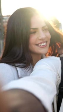 Şehirde selfie çekip arkadaşlıklarının tadını çıkarırken ve sıcak bir günbatımı arka ışıklarıyla anılar yaratırken mutlu, çoklu etnik gruptan genç insanlar gülümsüyor ve birlikte eğleniyorlar.