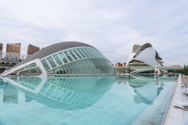 Valencia 'nın sanat ve bilim şehri fütüristik l' hemisferic ve palau de les arts reina sofia bulutlu bir gökyüzü altında sakin havuzlarda, parlak cam ve çelik mimaride yansıtılır.