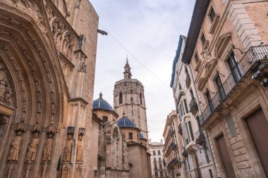 Gökyüzüne hükmeden miguelete kulesiyle Valencia Katedrali, süslü gotik mimari ve dar bir Avrupa sokağı boyunca uzanan geleneksel binalar