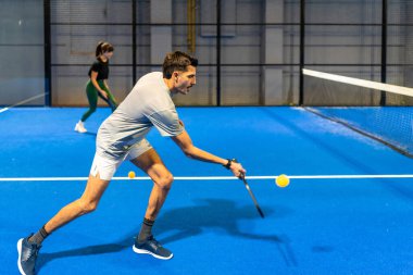 Sporcu, açık mavi bir sahada raketle sarı bir picleball 'a odaklanmıştı. Rekabetçi, enerjik ve hareketli bir oyun sırasında, yoğun ve hareketli bir oyun.
