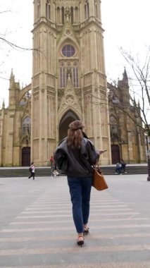 San Sebastian Katedrali 'nin iyi çobanına doğru meydanda yürüyen uzun saçlı şık bir kadın. Bask ülkesindeki tarihi gotik diriliş mimarisinin güzel bir örneği. İspanya.