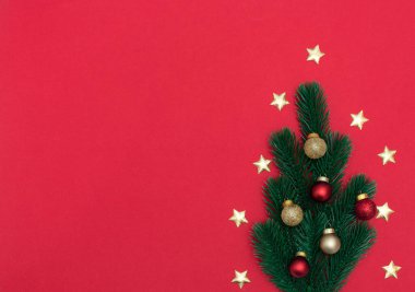 Kırmızı arka planda Noel süslemeleri olan ladin ağacından yapılmış bir Noel ağacı. Yeni yıl, kış tebrik kartı, poster. Kopya alanı ile düz uzanma biçimi. 