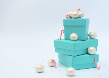 Mavi hediye kutuları, beyaz arka planda büyük ve küçük inci boncuklar. Seçici odaklanma. Noel ya da tatil, alışveriş zamanı. Noel ya da kış tebrik kartı. Yeni yıl tatili.