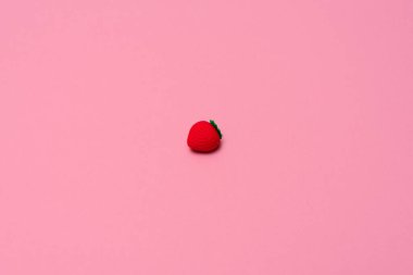 Pembe arka planda çilek şeklinde küçük silgi. Yaz zamanı, minimalizm konsepti. Kopya alanı ile düz uzanma biçimi